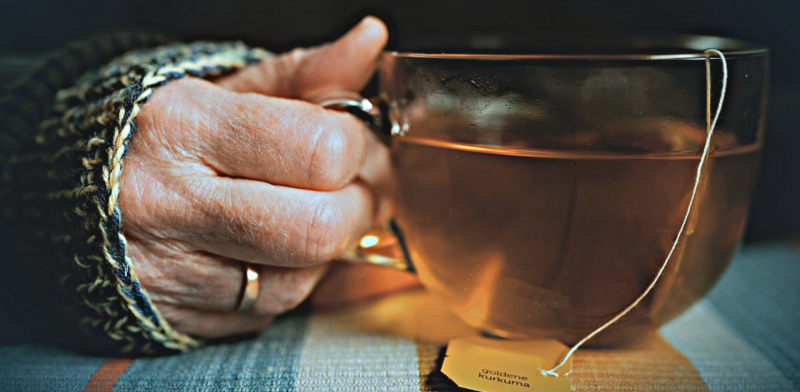 Imagen de una mano de una persona mayor asiendo una taza de té