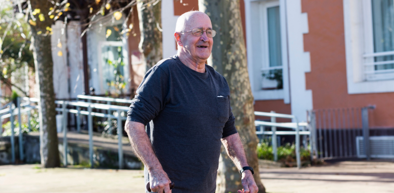 Imagen de un hombre mayor paseando con bastón por unos jardines