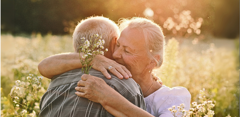 Pareja de personas mayores dándose un abrazo en pleno naturaleza