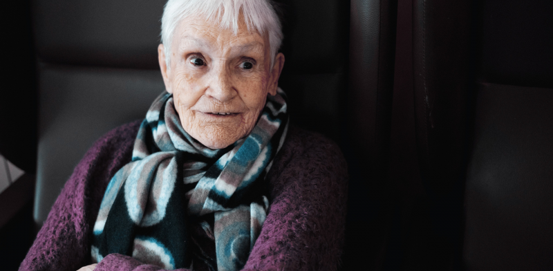 Fotografía de una mujer mayor sentada con una media sonrisa en el rostro