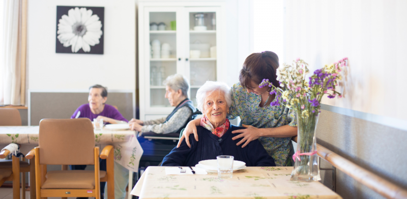 Imagen de una mujer mayor y su cuidadora en un comedor de una residencia