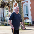 Imagen de un hombre mayor paseando con bastón por unos jardines